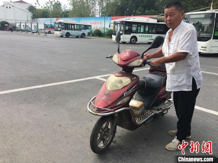 66岁的童助文骑着电瓶车到百神庙镇交通综合服务站取快递。　吴兰 摄